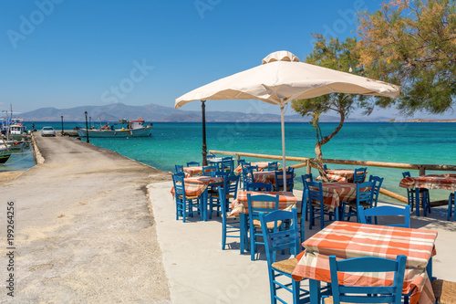 Fototapeta Naklejka Na Ścianę i Meble -  Tables with chairs in typical Greek tavern with view on sea bay. Agia Anna beach, Naxos Island. Greece.