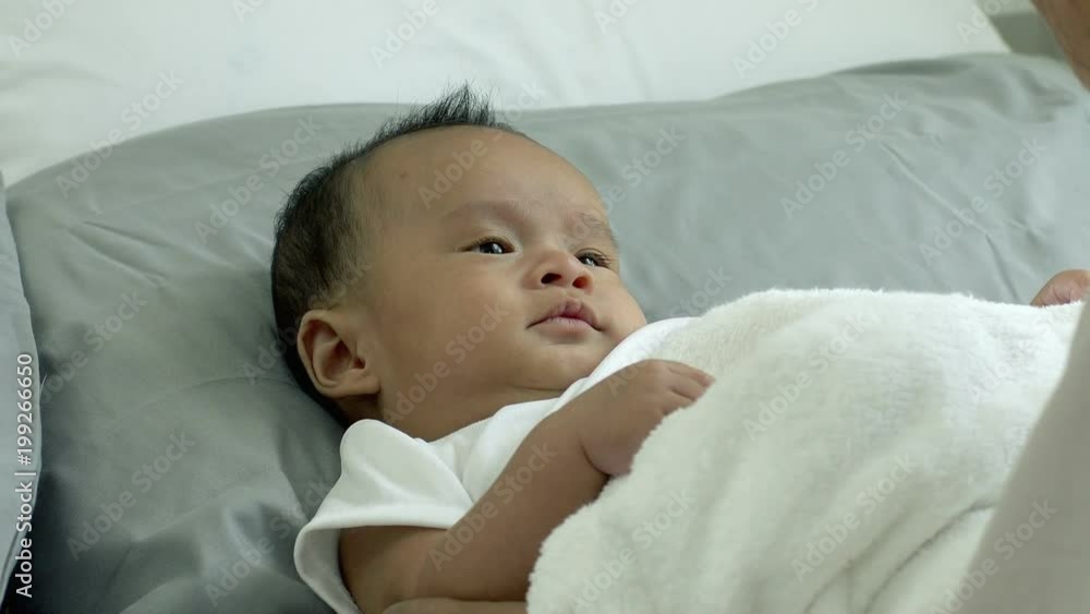 Young beautiful Asian mother caring and playing with her baby in the bedroom on a bright morning sunshine Young beautiful Asian mother caring and playing with her baby in the bedroom on a bright morning sunshine