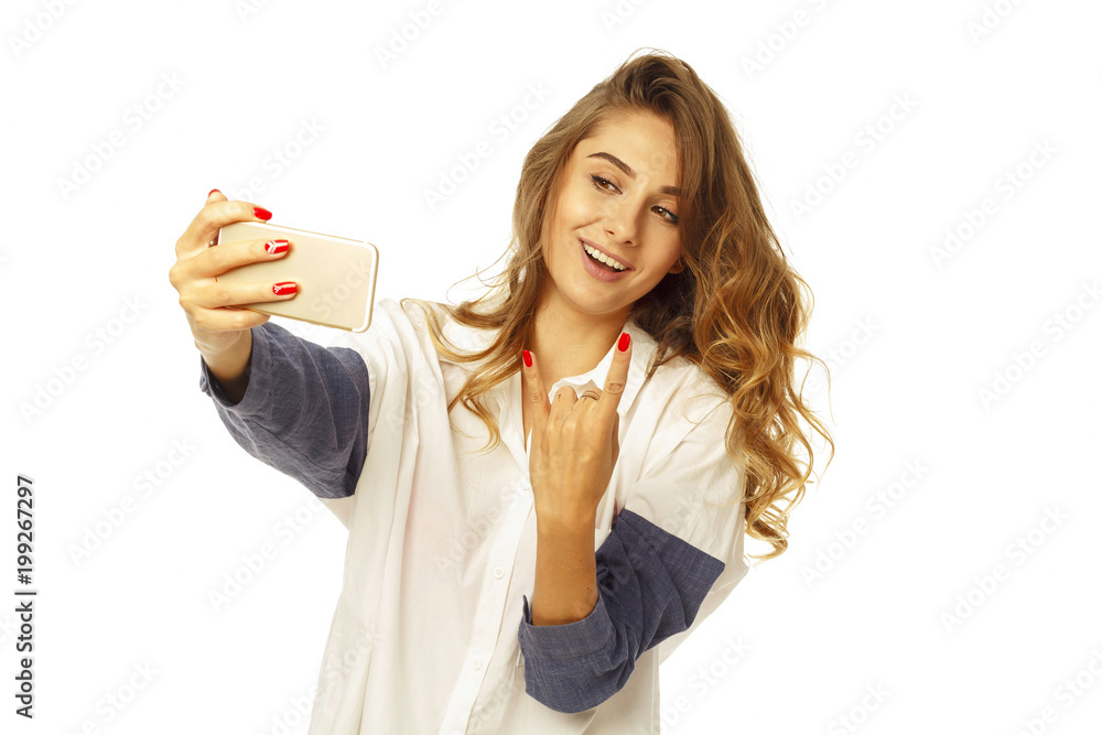 Portrait of a beautiful young woman making selfie on smart phone and showing devil sign. Happy woman photographing herself. Portrait of a beautiful young woman making selfie on smart phone and showing devil sign. Happy woman photographing herself.