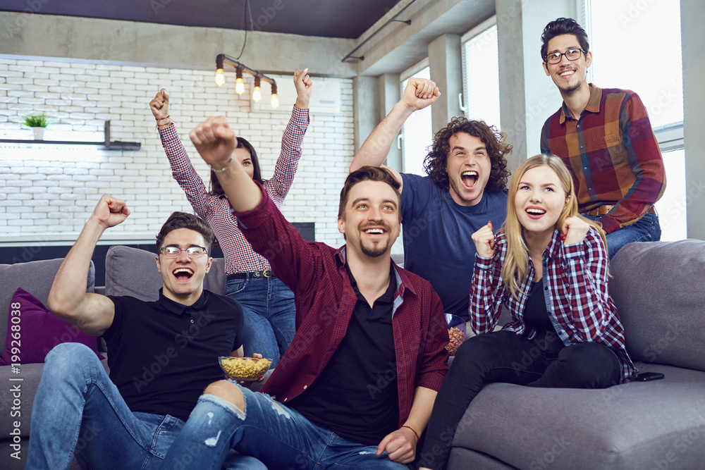 A group of friends at a party watching TV. Friends cheering for their team. A group of friends at a party watching TV. Friends cheering for their team.