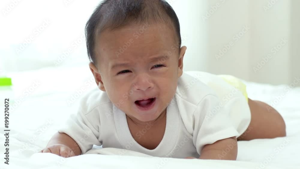 Young beautiful Asian mother caring and playing with her baby in the bedroom on a bright morning sunshine Young beautiful Asian mother caring and playing with her baby in the bedroom on a bright morning sunshine