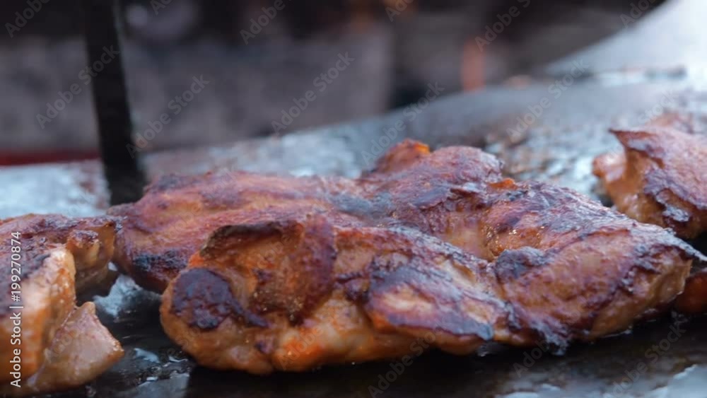 Close-up of raw chicken meat on the round barbecue. Street food. Close-up of the chef's hands that flip over raw chicken meat. Close-up of raw chicken meat on the round barbecue. Street food. Close-up of the chef's hands that flip over raw chicken meat.