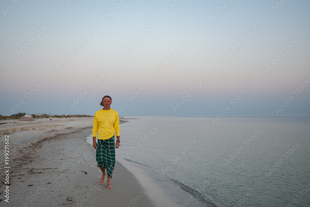 Joyful adventurer is walking along the surf line during sunset