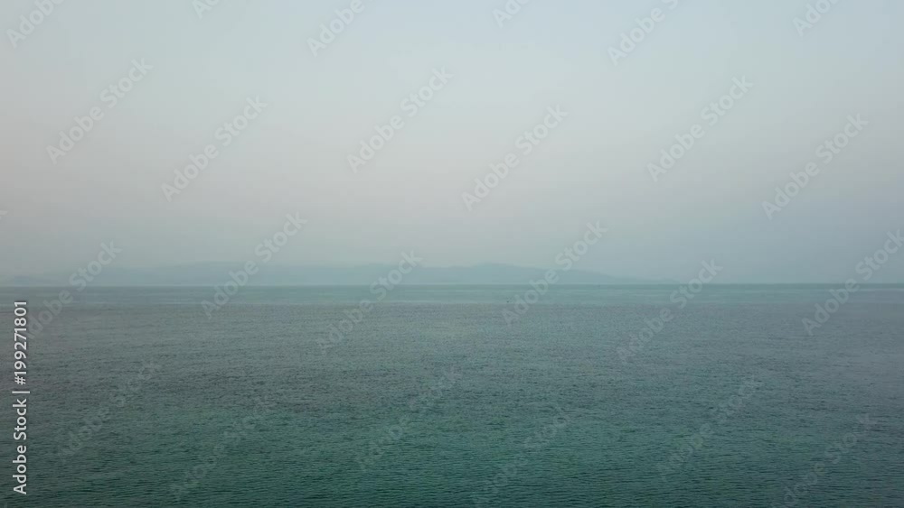 Aerial view over water approaching an island in background in Thailand