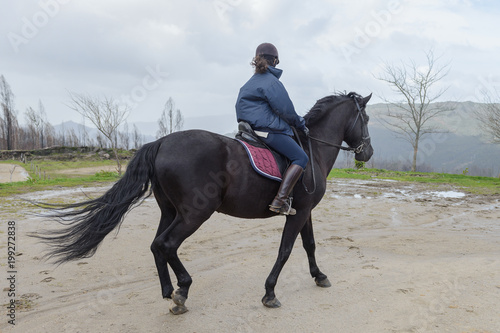 woman is riding a horse on a training ground