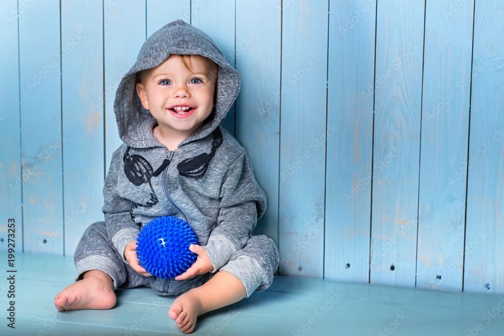 Image of sweet baby boy, closeup portrait of child, cute toddler with blue   boy sits, smiles and keeps the ball. Stock Photo | Adobe Stock