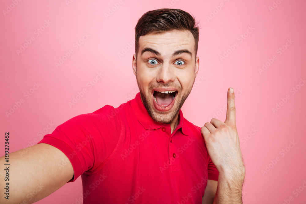 Portrait of a happy young man pointing finger up Portrait of a happy young man pointing finger up