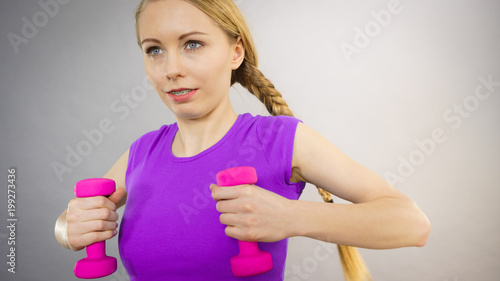 Teenage woman working out at home with dumbbell