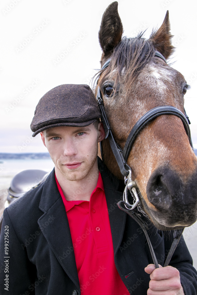Portrait of horse rider and brown horse. He is wearing a flatcap red polo shirt and black jacket Stock Photo Adobe Stock