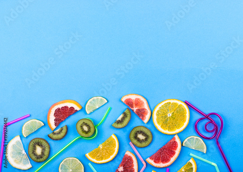 Citrus slices and straws on blue background