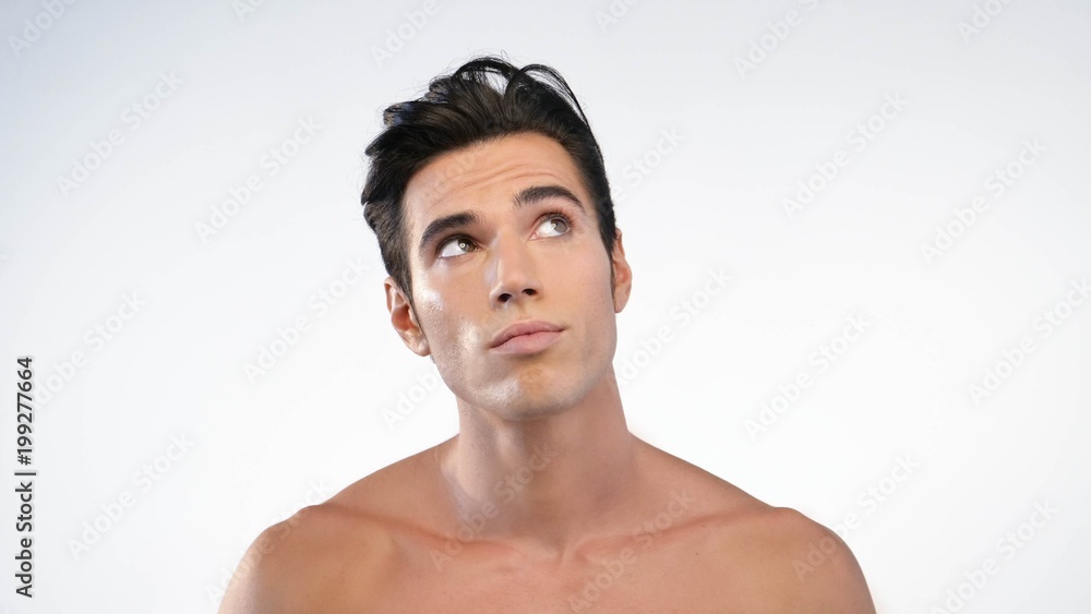 Fototapeta premium Close up of a man with moisturizer for his face smiling because he hydrates his skin and protects against impurities with anti-aging effects. Concept of: beauty and body care, creams, skincare