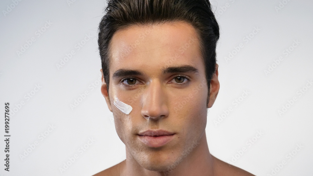 Close up of a man with moisturizer for his face smiling because he hydrates his skin and protects against impurities with anti-aging effects. Concept of: beauty and body care, creams, skincare Close up of a man with moisturizer for his face smiling because he hydrates his skin and protects against impurities with anti-aging effects. Concept of: beauty and body care, creams, skincare