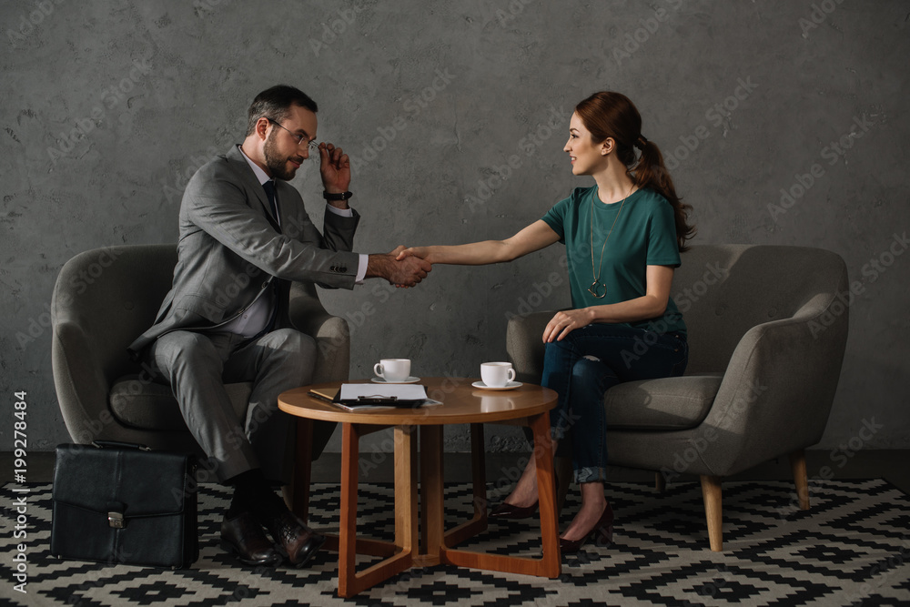 Obraz premium side view of woman and lawyer shaking hands while having meeting together