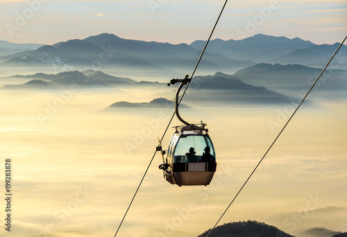 Ski lift cable booth or car, Ropeway and cableway transport sistem for skiers with fog on valley background