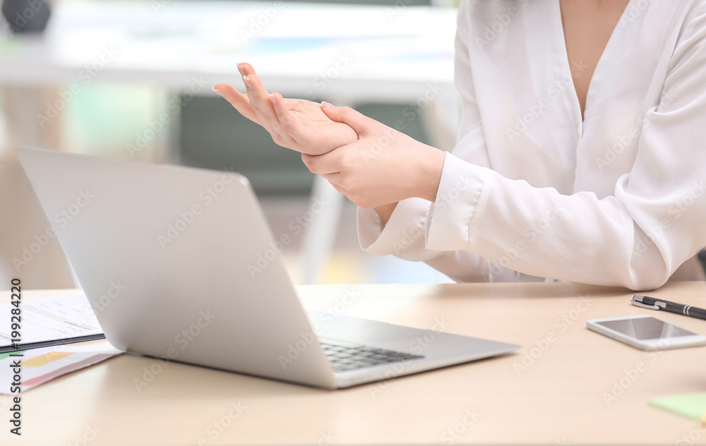 Young woman suffering from wrist pain in office Young woman suffering from wrist pain in office