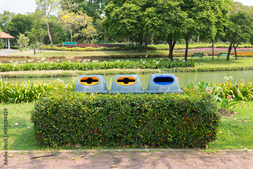 Color trash containers for separate garbage in plant. Trash bin along the way in public park. Garbage separate bin in park.