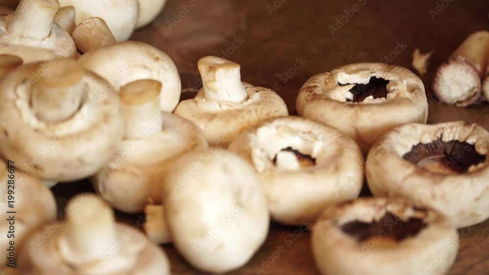 Woman breaks off legs of mushrooms and puts them on table Woman breaks off legs of mushrooms and puts them on table