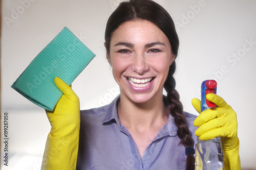 A beautiful woman struggling with house cleaning cleans the house with a spray and a cloth on purpose. Concept of: cleaning, perfection, domestic crafts, cleaning products.