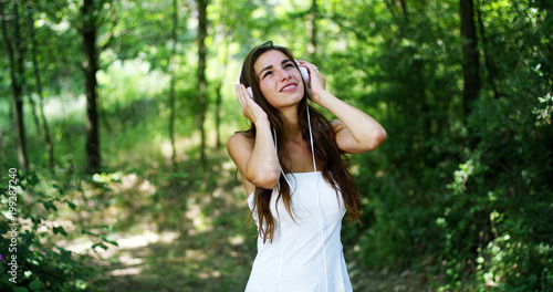 A woman in the green wearing headphones listening to music, singing, dancing and having fun with an air carefree. The music gives him the energy to sing and be happy. music makes flying imagination