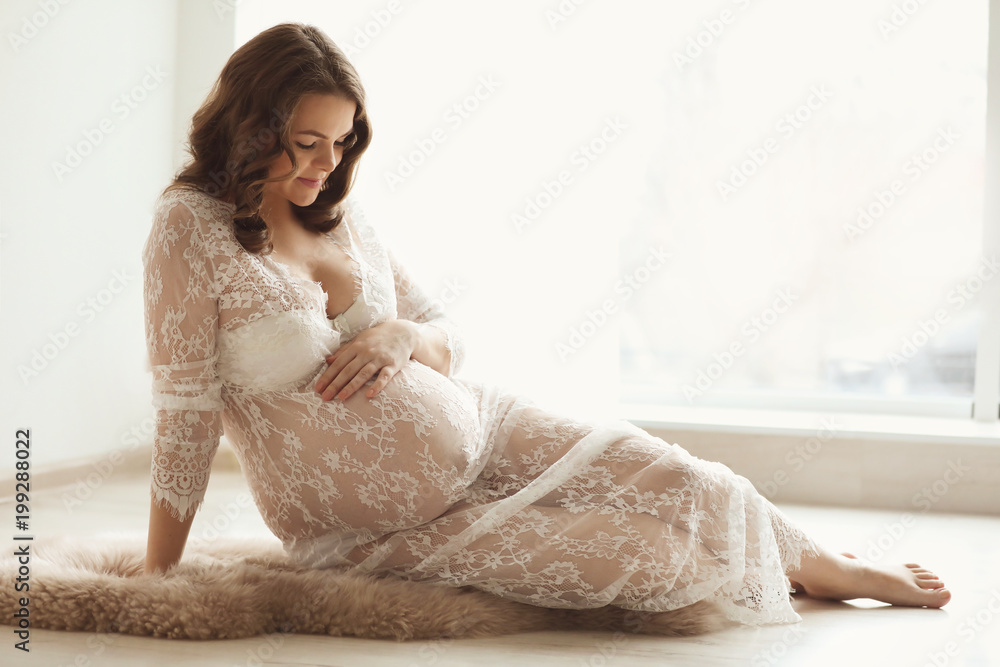 Naklejka premium Young pregnant woman in elegant dress at home