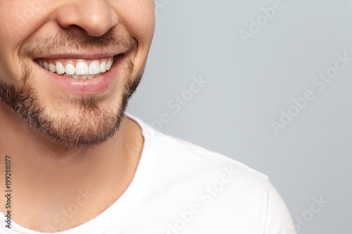 Fototapeta Naklejka Na Ścianę i Meble -  Young man with beautiful smile on grey background. Teeth whitening