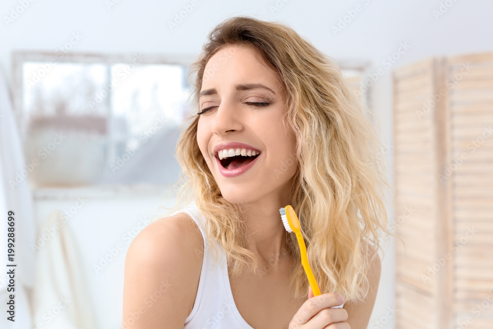 Young woman brushing her teeth in bathroom Young woman brushing her teeth in bathroom