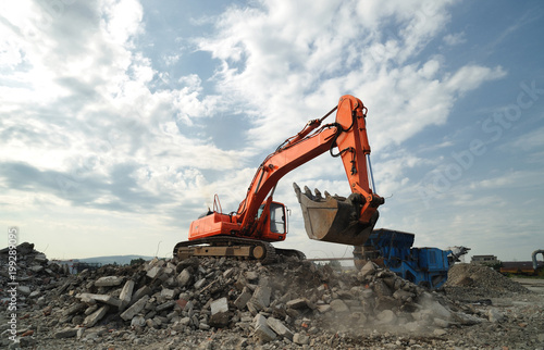 Working activity on demolition construction site. Crawler excavator and stone breaker machinery working on demolition site.