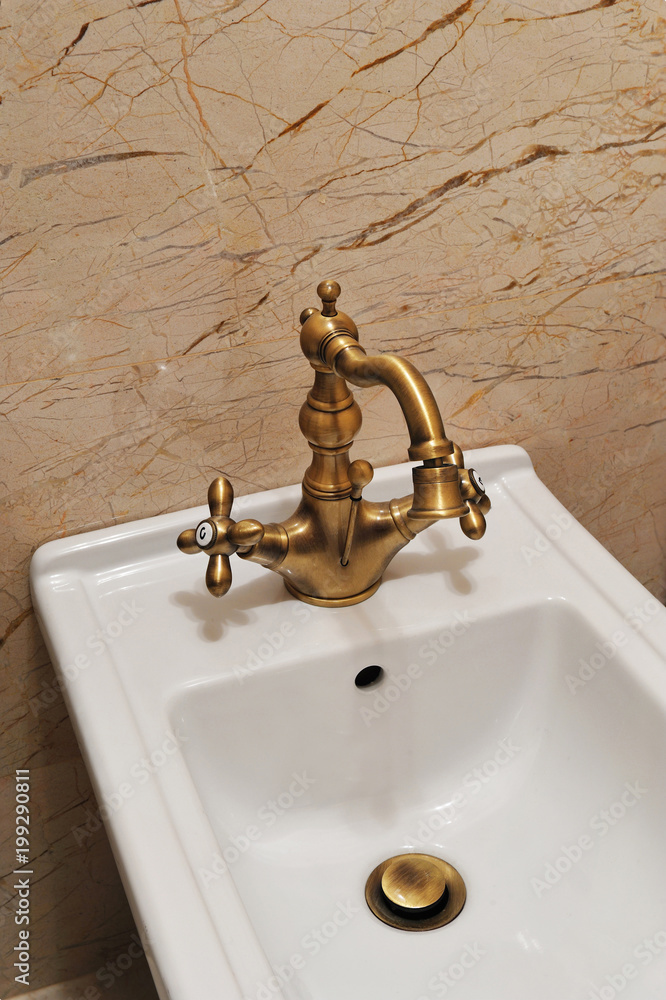 Bidet accessories for bathroom. White bidet with golden vintage water tap inside bathroom. Stock Photo | Adobe Stock