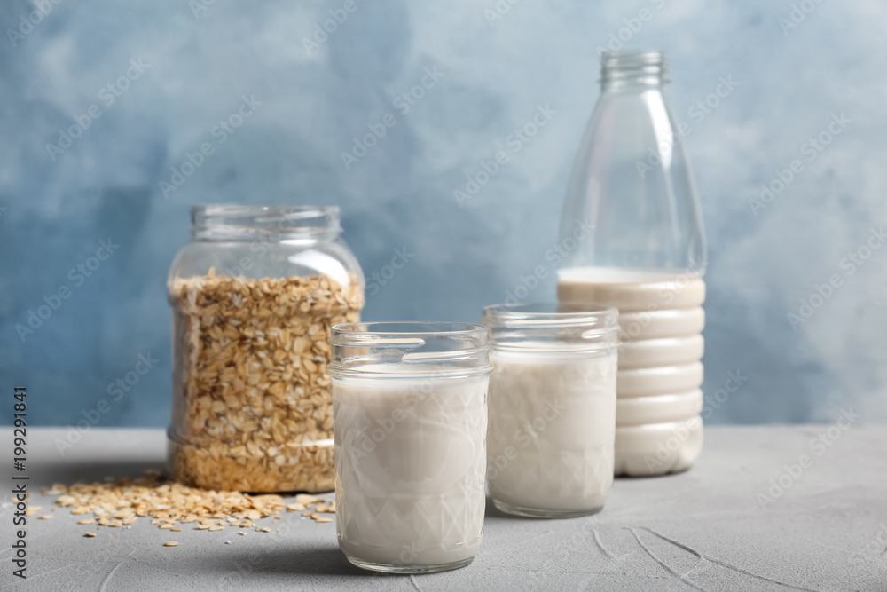 Jars with oat milk and flakes on table Jars with oat milk and flakes on table