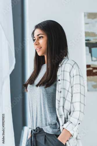 Attractive smiling girl standing and looking in window