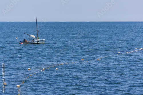 fishermen on a wooden boat hunt fish in the sea with rods and nets.beautiful blue and crystal clear water in the summer season. fishing in the ocean. © Ivan