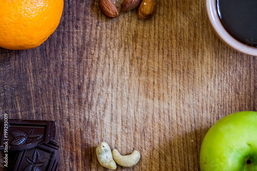 Fototapeta Naklejka Na Ścianę i Meble -  Healthy food. apple, orange, nuts, dark chocolate and black coffe