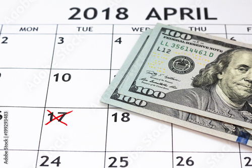 Calendar showing tax day for filing is April 17 2018 and 100 dollar bills photo