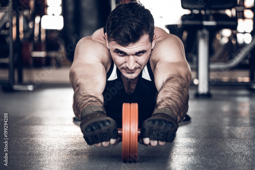 Young athlete excersises with barbell ab rollout photo