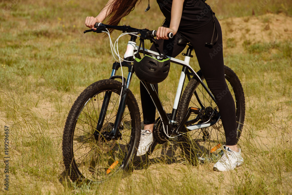 Obraz premium Bicyclist at the summer sunset on the desert road in the reserve territory. Full length image of female bicycle. Extreme mountain bike sport athlete woman riding outdoors lifestyle trail