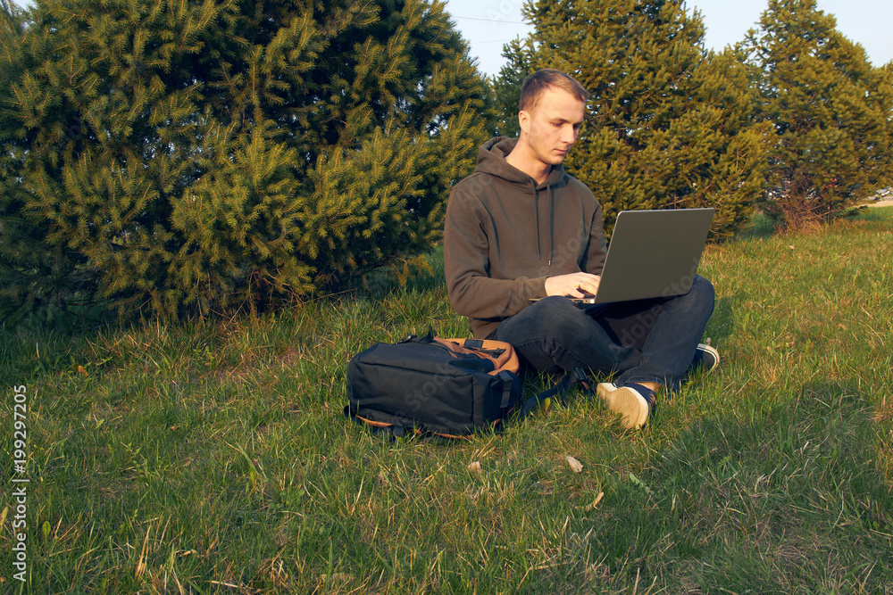 young man working in laptop sitting on grass young man working in laptop sitting on grass