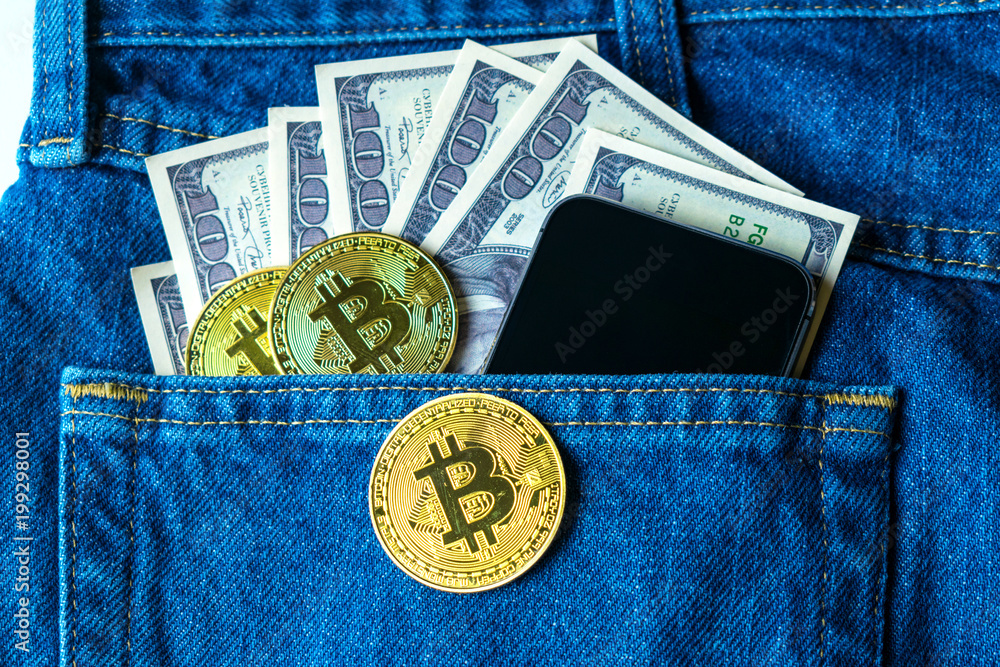 Golden bitcoins and large stack of money with modern smartphone in the pocket of old vintage indigo stonewashed jeans. Concept of daily things of modern man. Trendy color Golden bitcoins and large stack of money with modern smartphone in the pocket of old vintage indigo stonewashed jeans. Concept of daily things of modern man. Trendy color