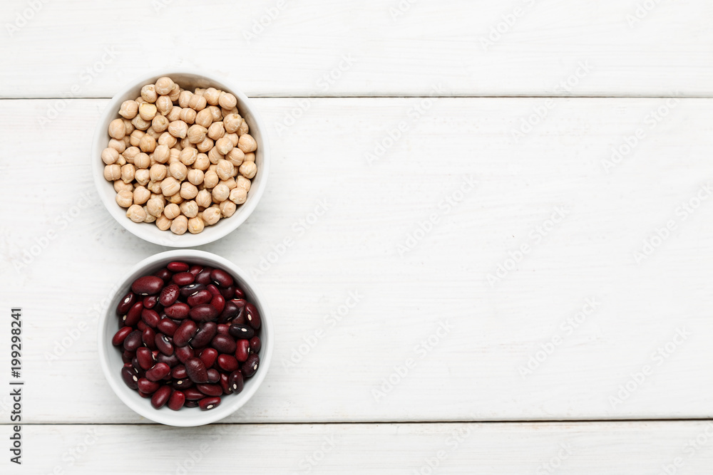 Different beans in bowls on a white wooden table, top view Different beans in bowls on a white wooden table, top view