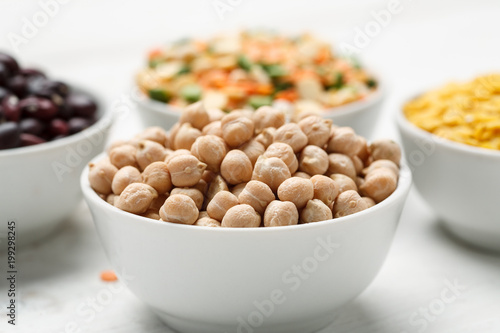 Chickpea and other beans in white bowls on a wooden table