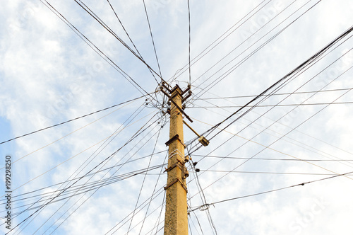 Many wires strained on one power line pole on the background of the sky