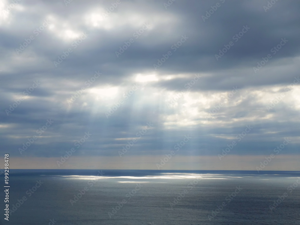 Sunlight shining through clouds over the sea.