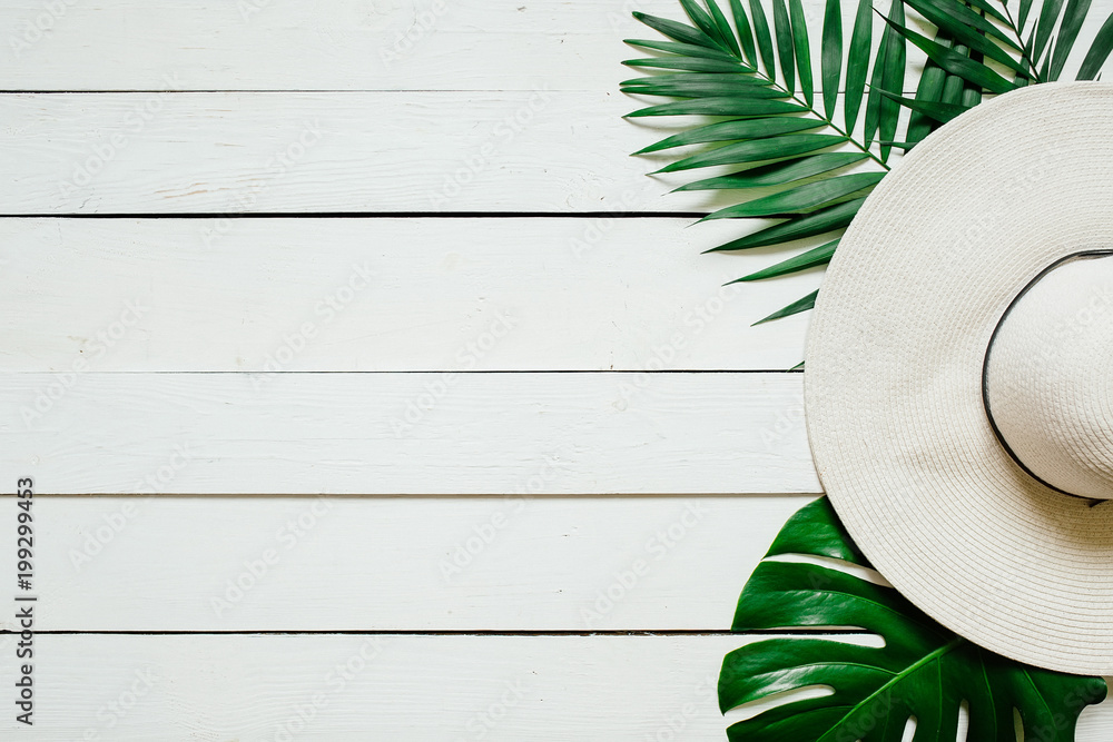 White straw hat, green plam leaves on wooden baclground. Summer holidays vacation concept. Poster banner, postcard template. - obrazy, fototapety, plakaty 