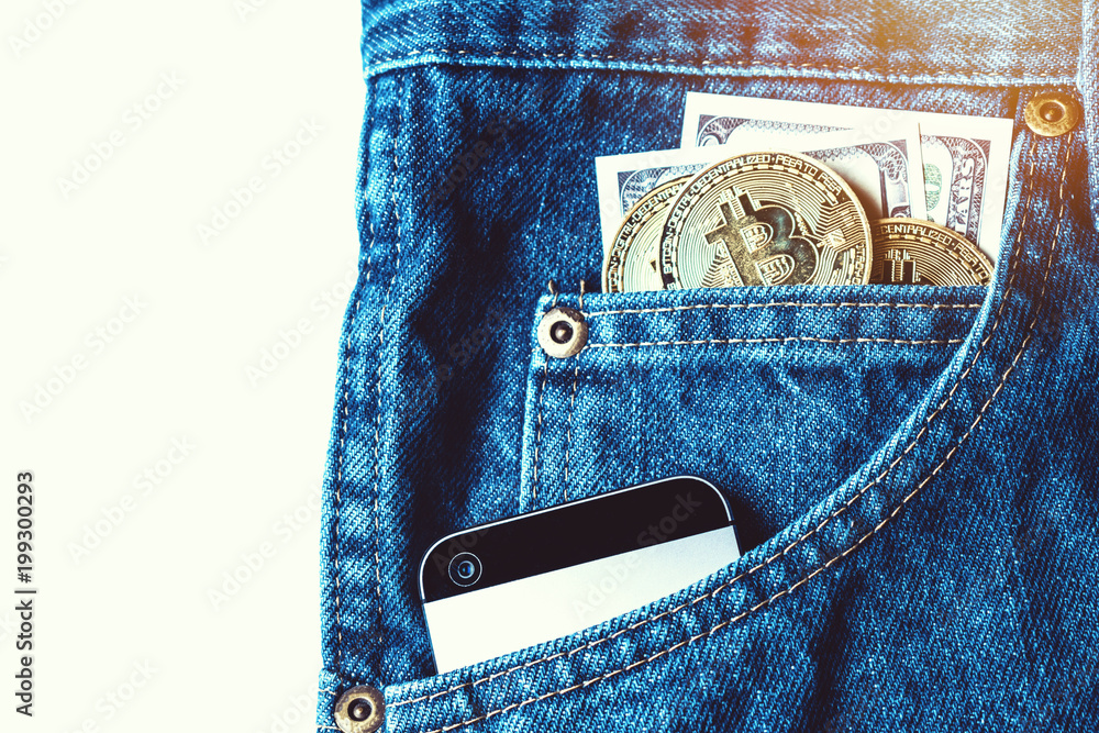 Golden bitcoins and large stack of money with modern smartphone in the pocket of old vintage indigo stonewashed jeans. Concept of daily things of modern man. Trendy color Golden bitcoins and large stack of money with modern smartphone in the pocket of old vintage indigo stonewashed jeans. Concept of daily things of modern man. Trendy color