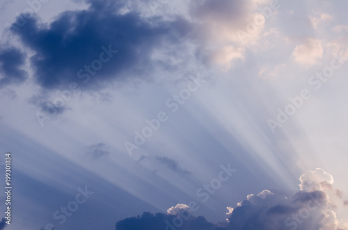 Unusual sun rays penetrating through beautiful thick fluffy clouds on the blue sky in a hot summer day. Beautiful cloudscape background or backdrop for your graphic design © Gabriel