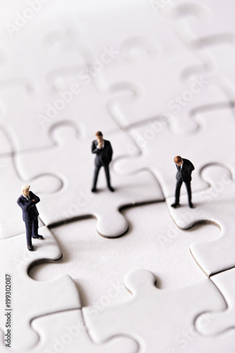 Miniature men on jigsaw puzzle