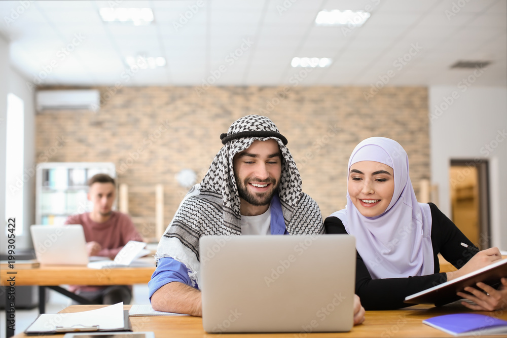 Muslim students in traditional clothes studying indoors Muslim students in traditional clothes studying indoors
