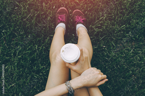 Sport young asian woman sitting on grass, drinking coffee. Resting Runner. Vintage filter.