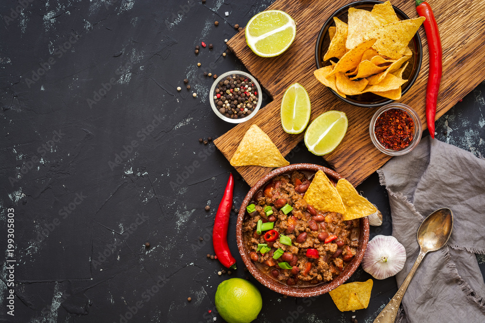 Chili con carne with nachos chips on rustic background.Mexican food. Place for text, top view.