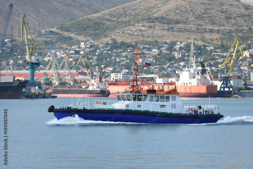 A small blue boat on the background of the port with loading ships