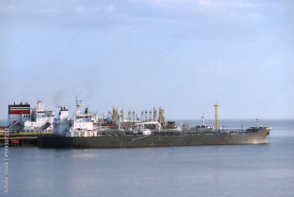 A large tanker is moored at the dock. Tanker against the blue sky in the port